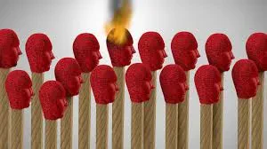 A conceptual illustration of a row of matchsticks with red heads shaped like human profiles, with one matchstick head catching fire to symbolize burnout or stress.