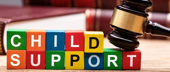 An image showing colorful wooden blocks that spell out "CHILD SUPPORT" arranged in two rows, with a wooden judge's gavel resting on top of the last block on the right.