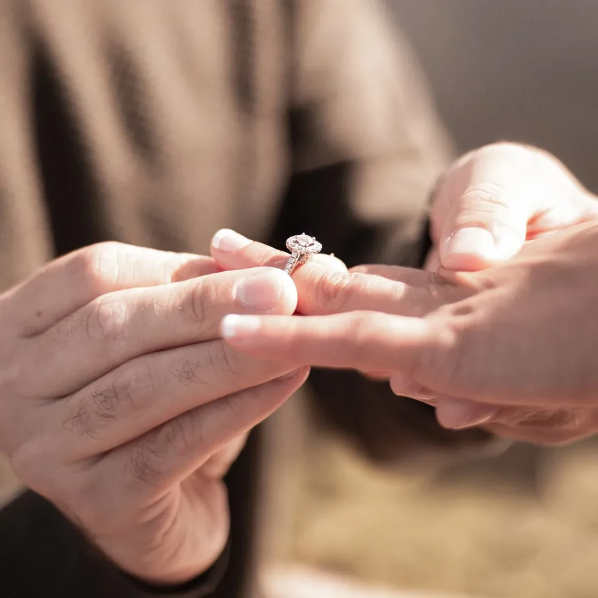 A man gently places a ring on a woman's finger during a proposal, capturing a moment of love and commitment.